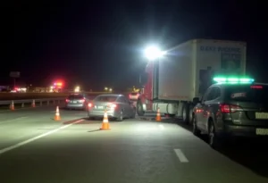 A highway accident scene involving an 18-wheeler truck and a sedan