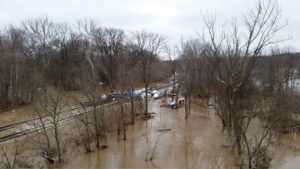 Muddy floodwater spreading over low ground and rail tracks
